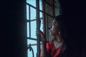 柔和光線中一位女性獨自望向窗外，象徵人類圖關係裡等待一個不存在的人