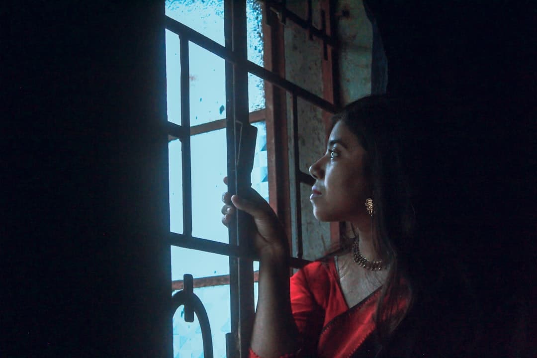 柔和光線中一位女性獨自望向窗外，象徵人類圖關係裡等待一個不存在的人